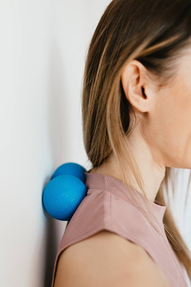 woman using massage balls against a wall